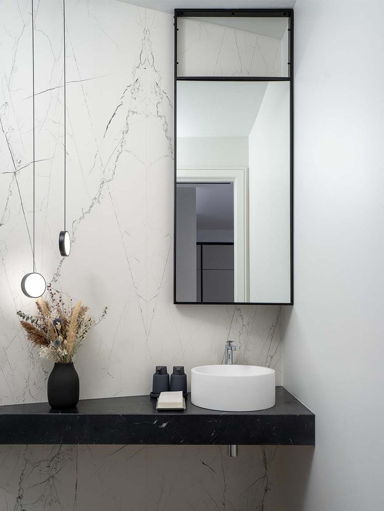 Vertical black mirror over corner basin in powder room