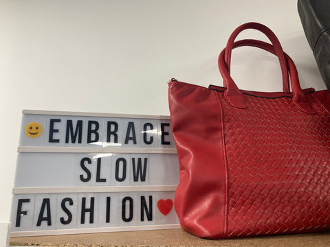 Embrace slow fashion sign with red handbag