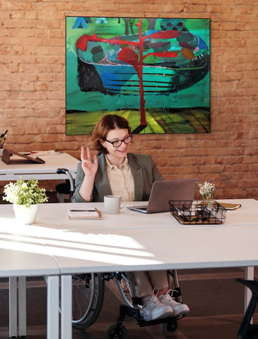 Confident woman on a video conference in her office with WheelHouse Art in the background