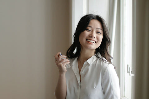 A lady spraying perfume on the neck