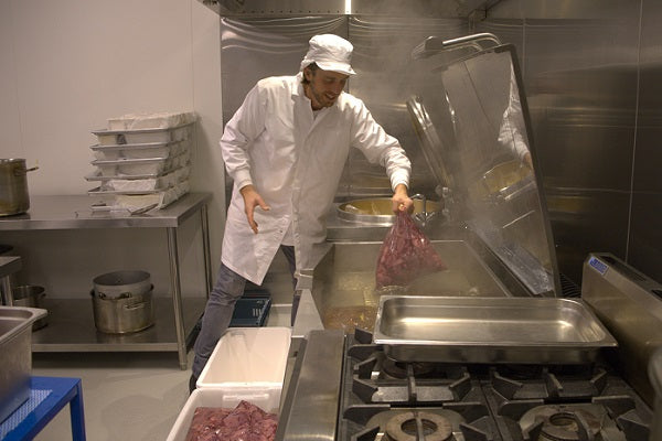 chef smiling while cooking loading in livers into professional cooking equipment