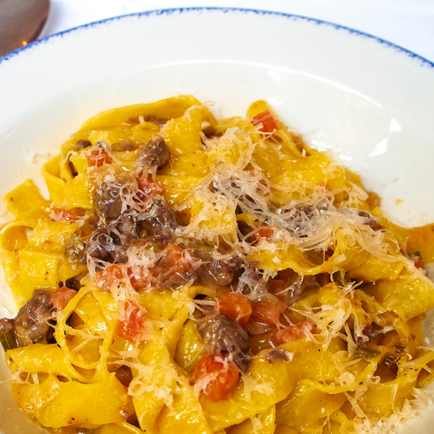 yellow thick pasta in a bowl with sauce with meat