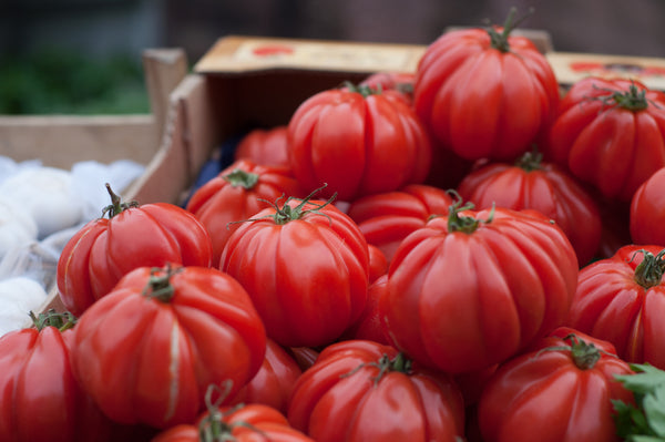 several large ripe tomatoes in a pile in a wodden box