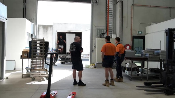 men standing around moving truck inside factory