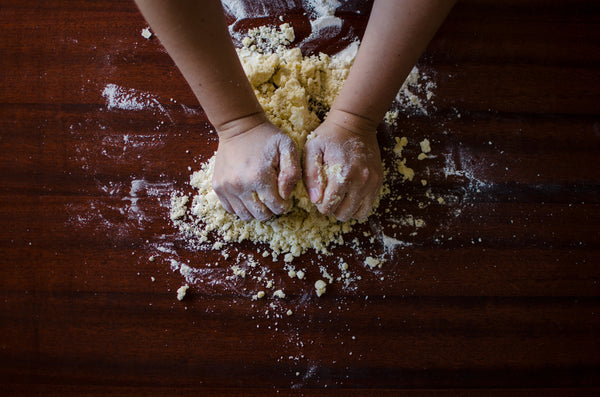 kneading pasta dough on a wooden board