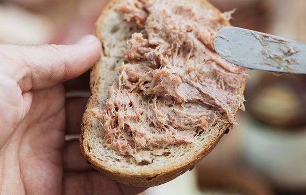 spreading city larder rillettes on piece of toast held in hand
