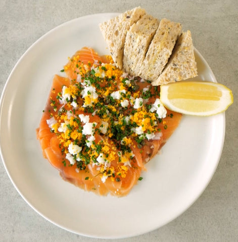 white plate with slices of smoked salmon lemon and bread