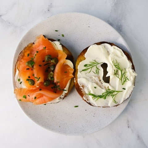 bagel with cream cheese and smoked salmon on white plate marble background