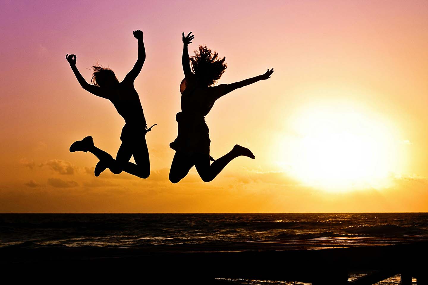 Two people in silhouette jumping in the air