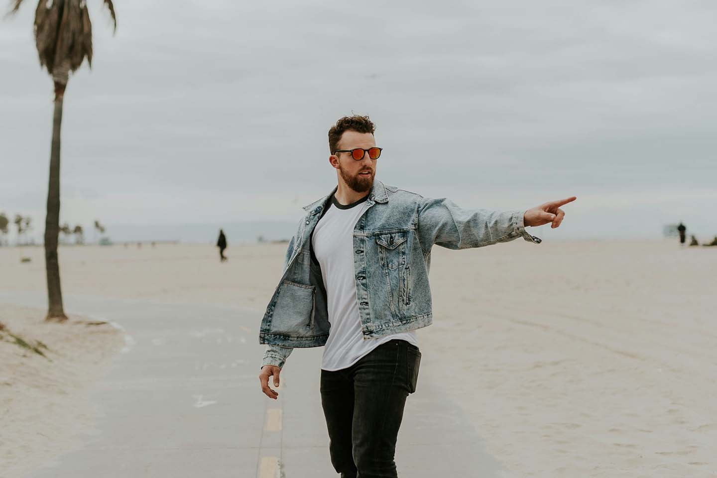 man in the middle of the street looking and pointing at something to his left side