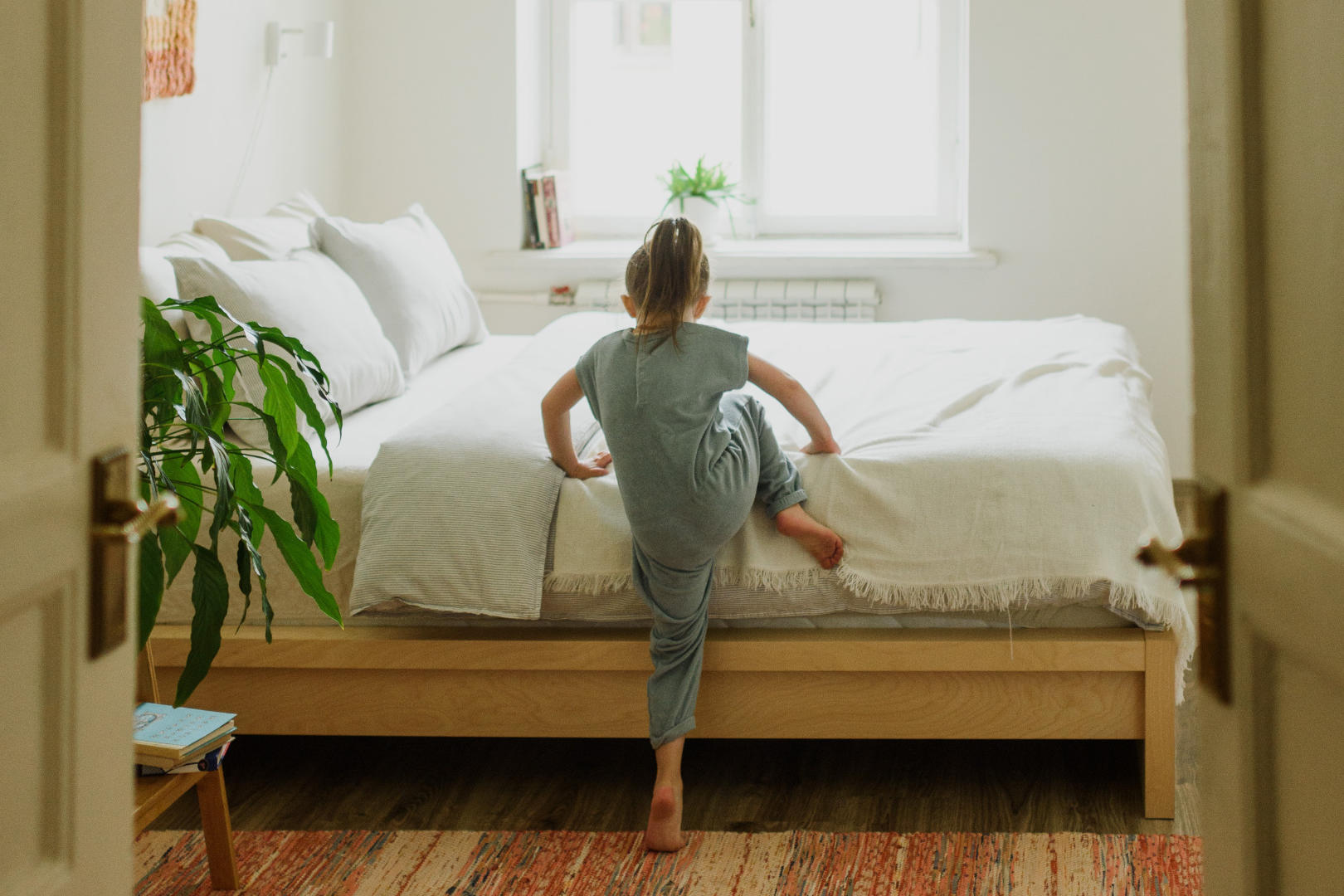 A girl climbing onto bed in a modern bedroom.