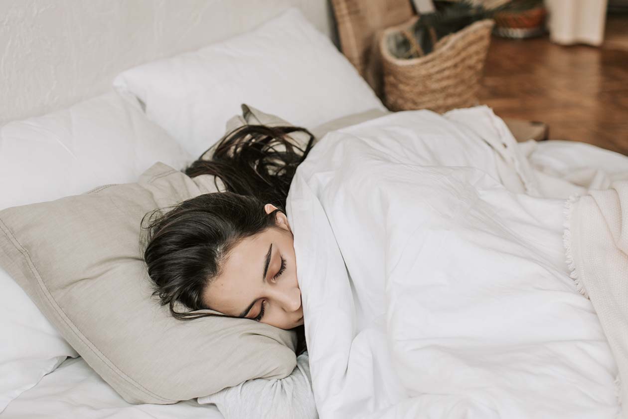 woman sleeping on bed tucked with white blanket