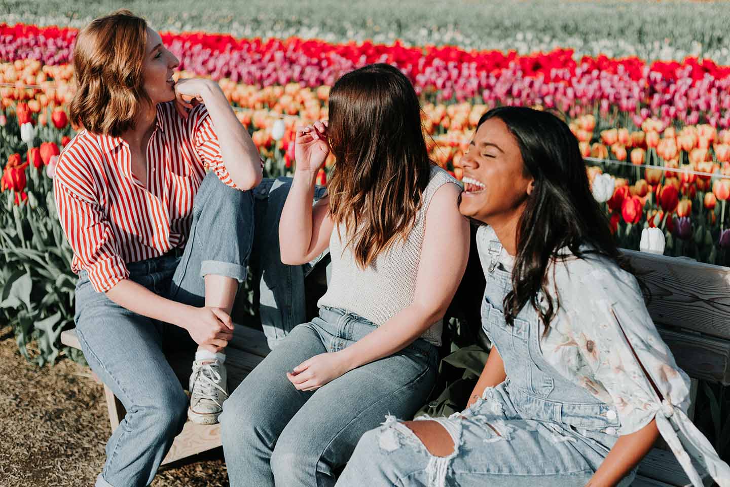 three women laugh in front of colorful tulip fields