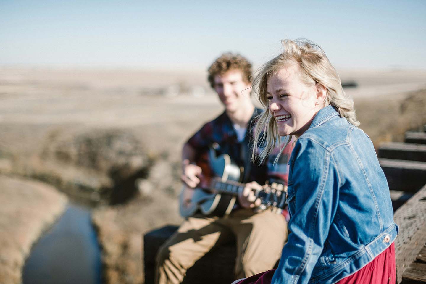 man plays guitar while woman smiles