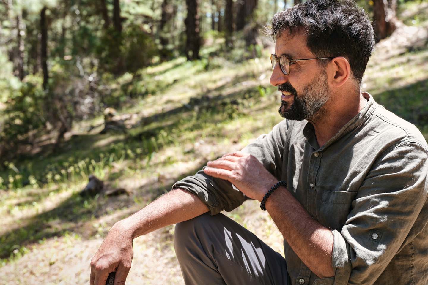 man in gray shirt sitting on green grass field during daytime