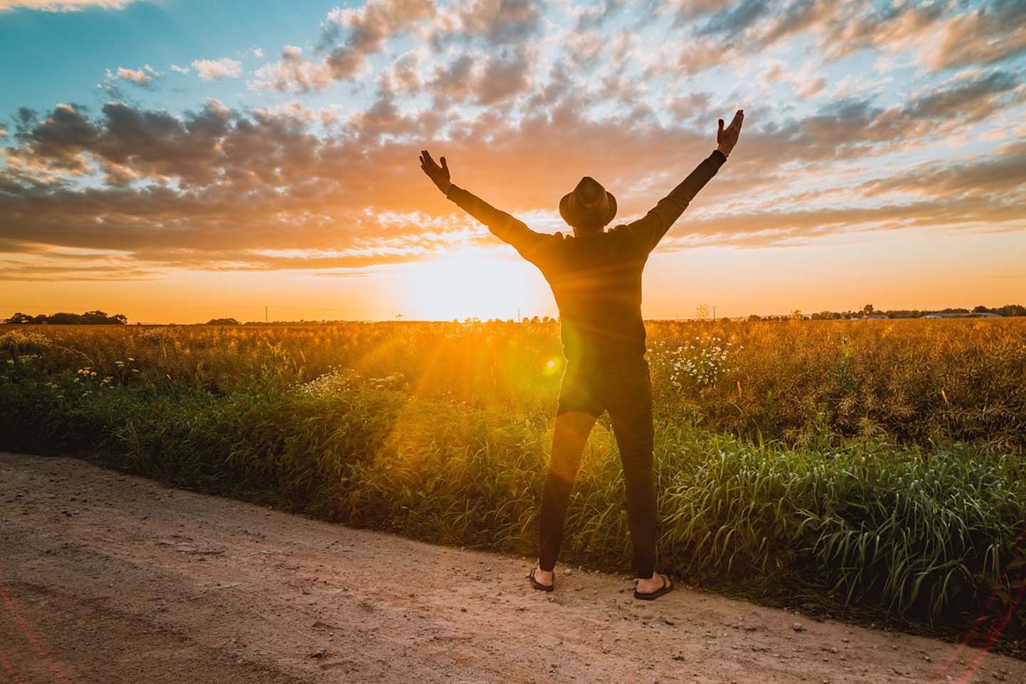 Man with arms raised at sunset