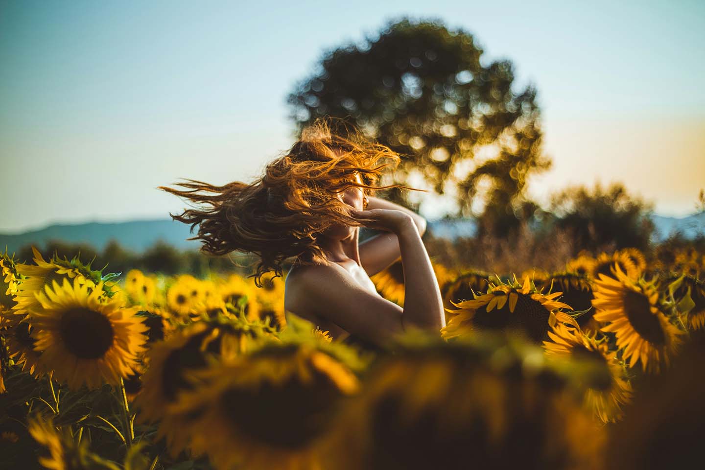 woman standing in a vibrant field of sunflowers, basking in the golden glow of the sun's rays