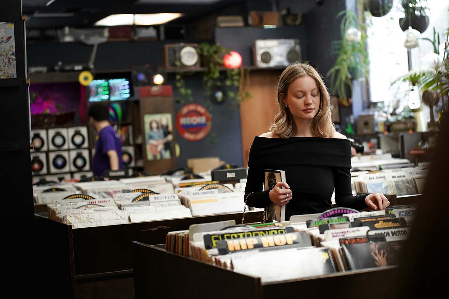 a woman selecting a product from a record store
