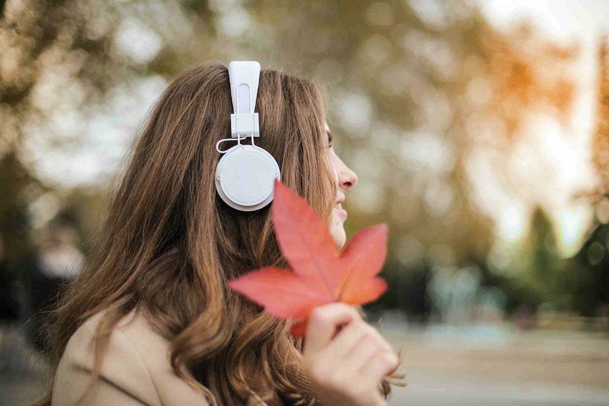 Woman wearing headphones holding a red leaf