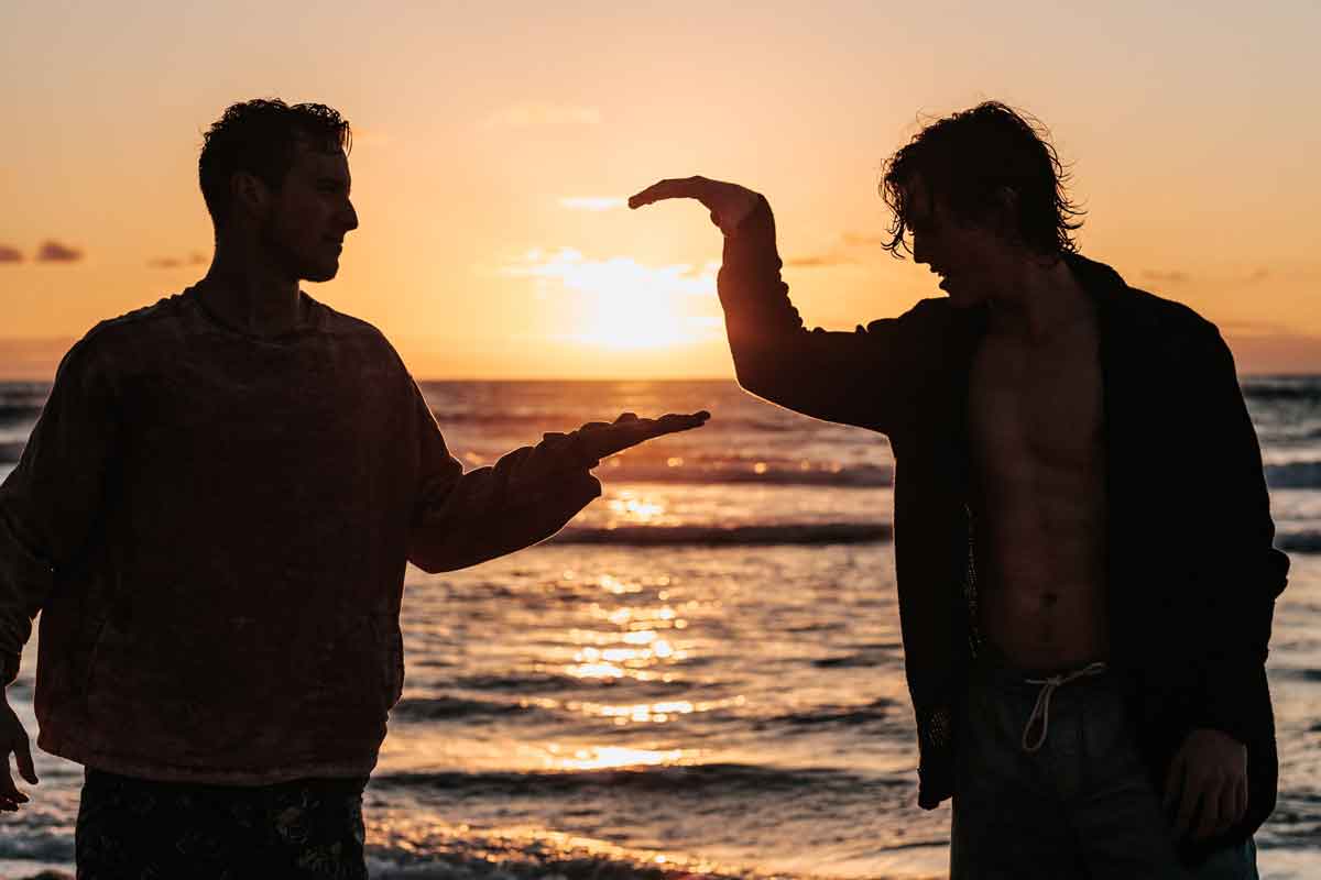 two men having a great time on the beach at sundown