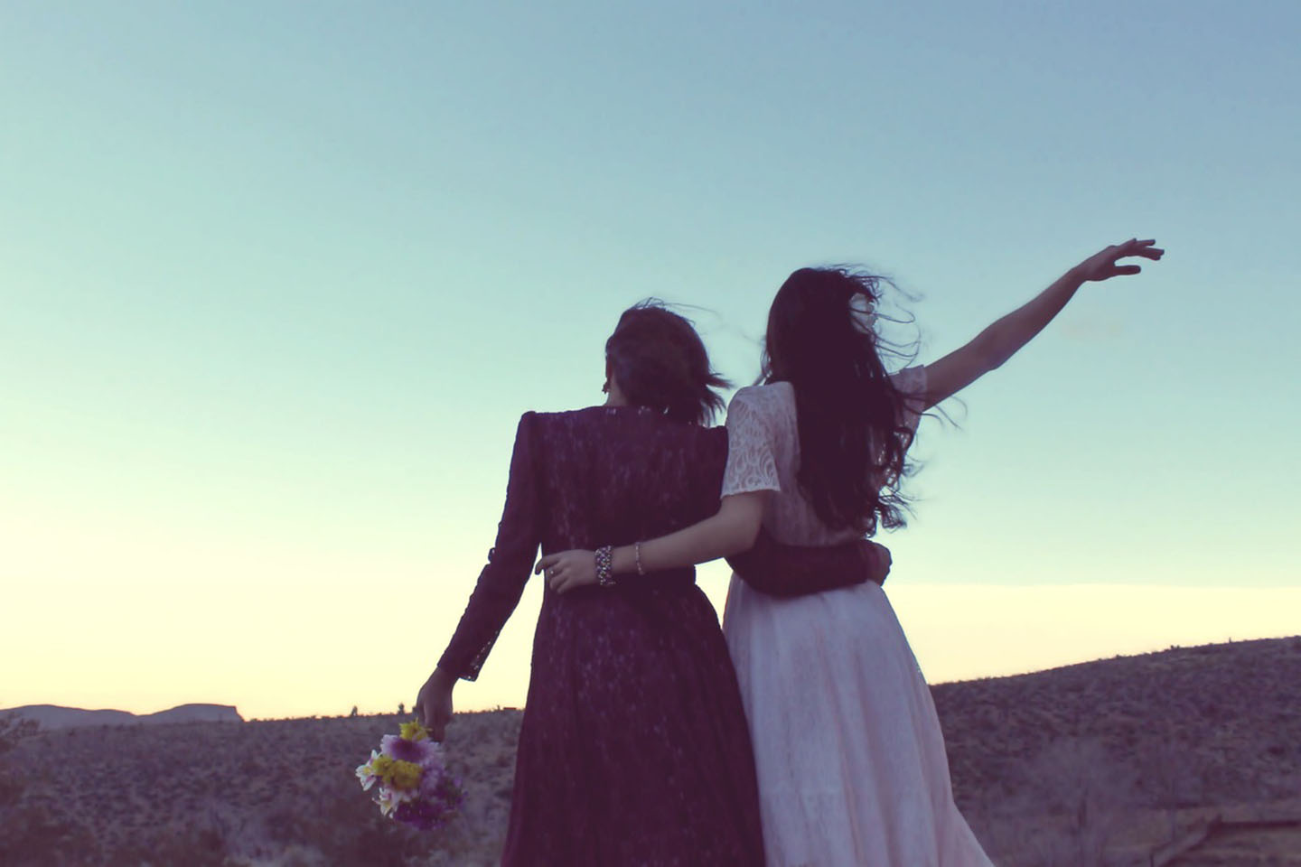 two women in dresses watching the sunset