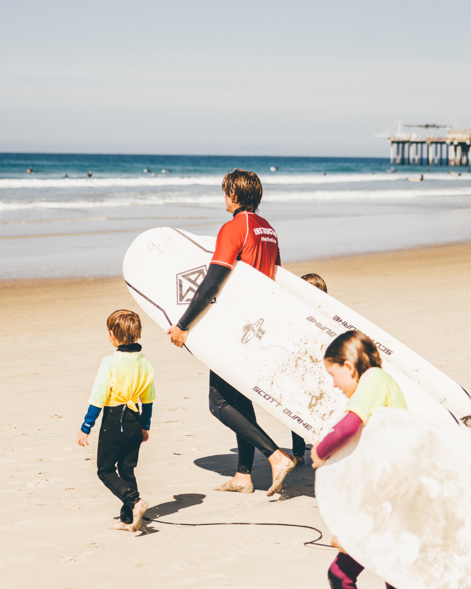 a surf instructor in San Diego giving two kids a lesson