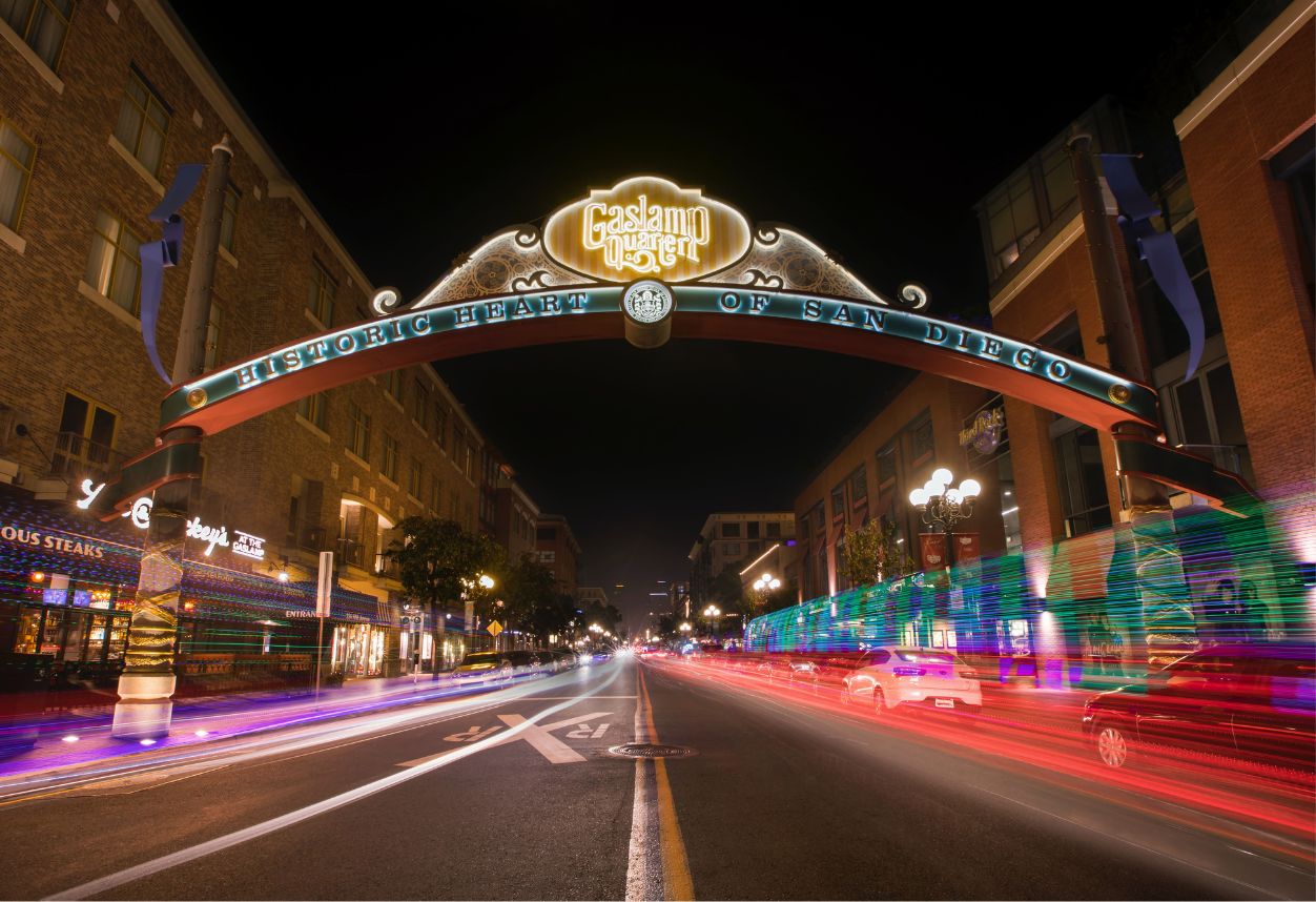 Nightime lit up sign of Gaslamp Quarter in San Diego with cars driving by.