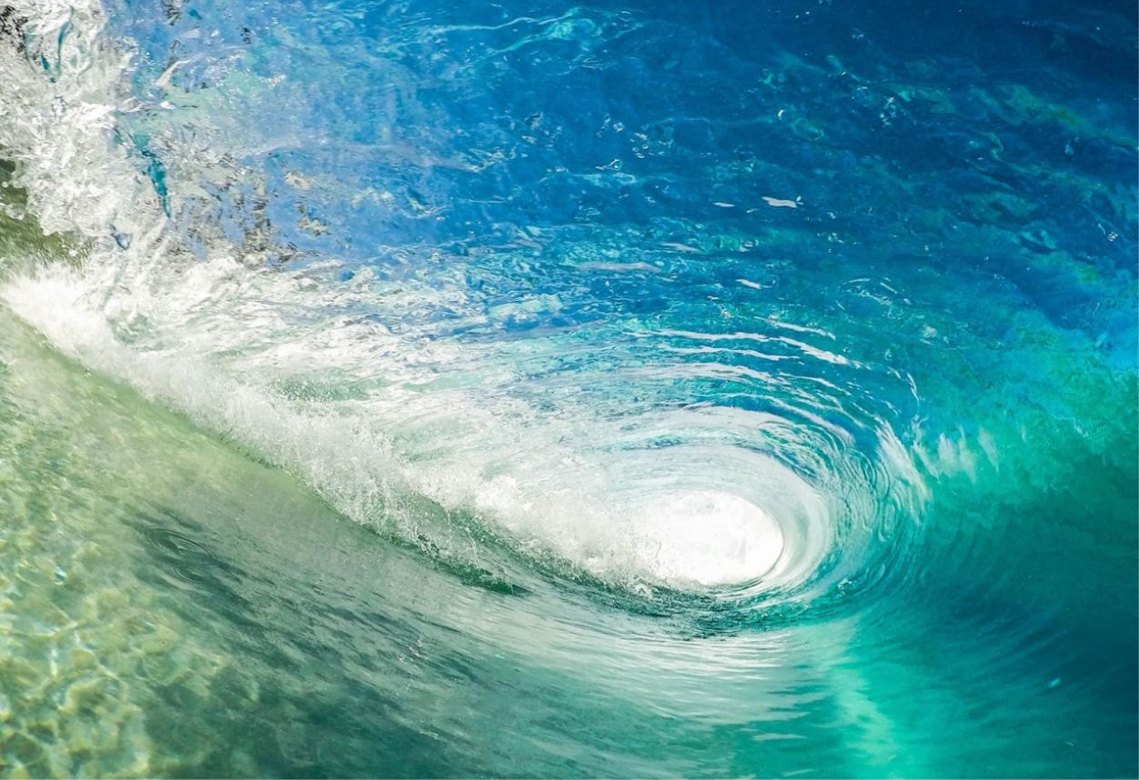 side view of light blue and green clear water wave.