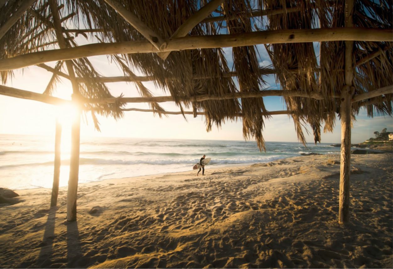 Wind and sea beach. Large tropical hut on the beach with the sun setting in the background.