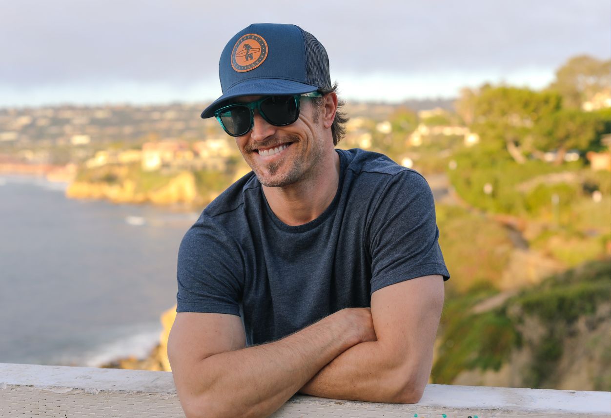 man on the cliffs on California overlooking the ocean with an everyday California hat on and sunglasses