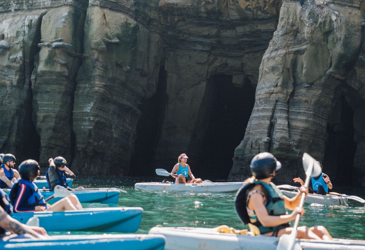 A kayak tour with multiple boats in front of the La Jolla seven sea caves