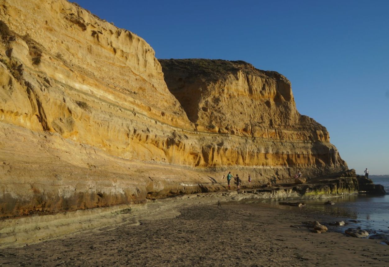 The coastal cliffsides of Black's Beach in Torrey Pines, California. Rocky sandy mountains and ocean coming to high tide