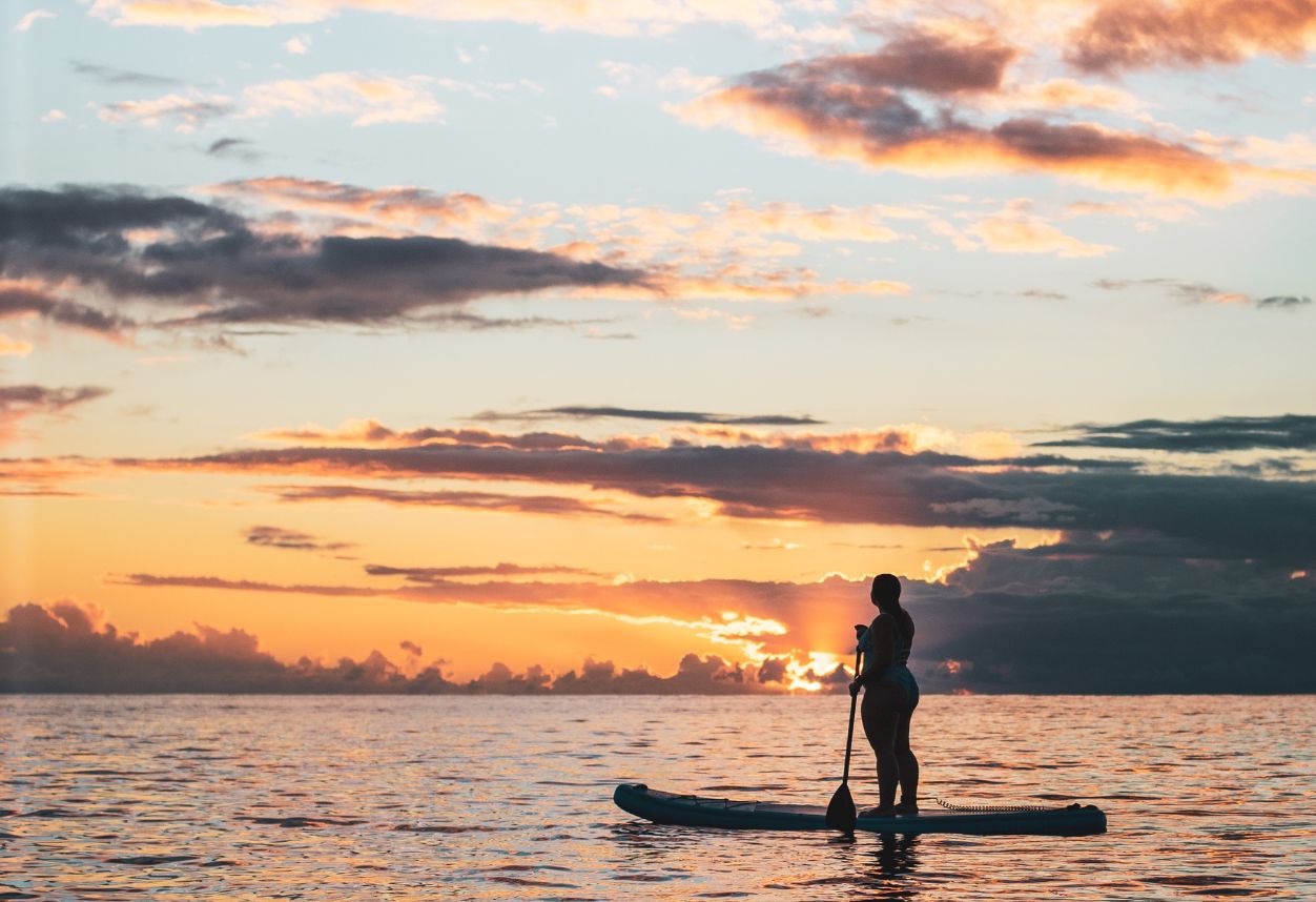 a girl on an inflatable paddle board in San Diego California during sunset