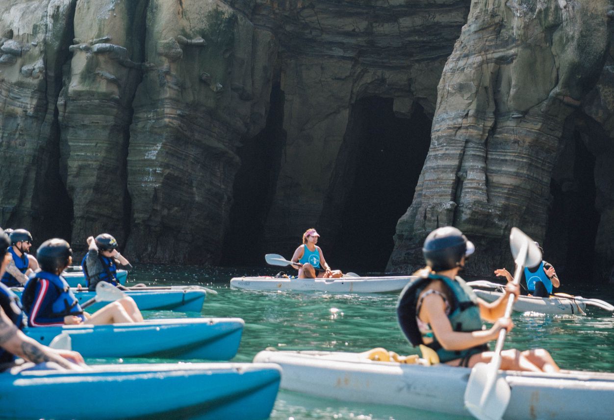 a group of kayakers on a guided tour that are in front of the La Jolla seven sea caves looking for sea lions