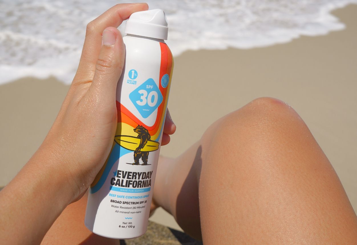 Reef Safe No Aerosol Sunscreen Everyday California being applied to legs on the beach