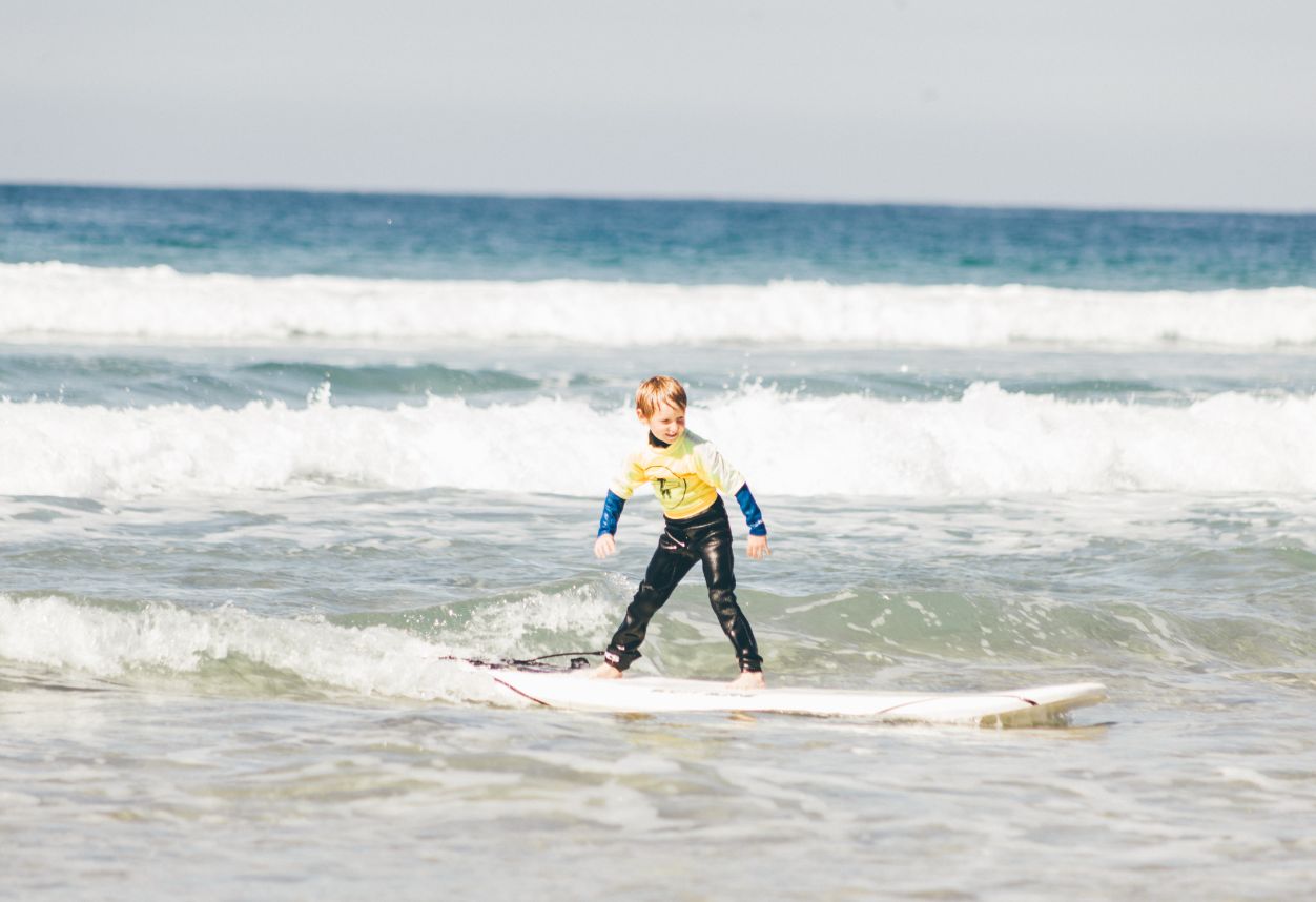 very small kid on a longboard surfing on an everyday California surf lesson