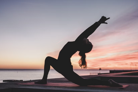 Woman doing yoga with sunset in the background