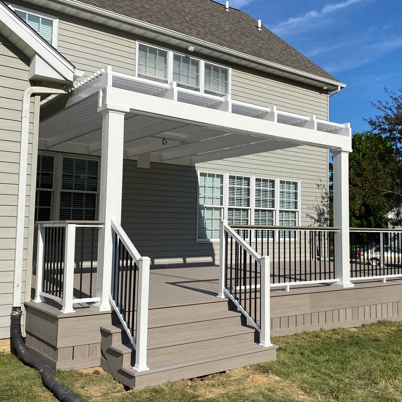 Outside view of a traditional white pergola covering a back patio with no overhangs and flat end caps so as to look more like a modern-style pergola