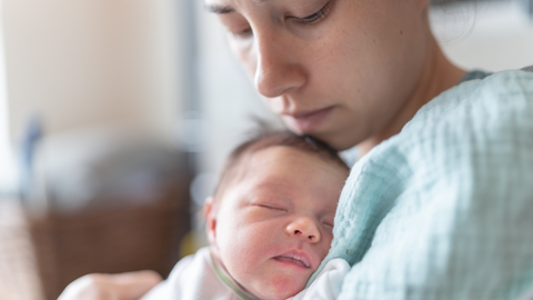 close up of face of young mom holding newborn infant