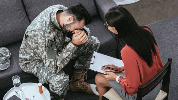 Soldier with his head in his hands sitting across from female therapist