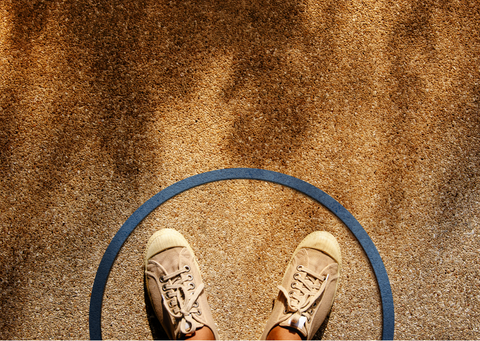 feet in sneakers seen from above, with a blue circle around the feet.