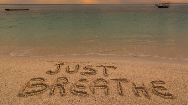 A beach with the words just breathe drawn in the sand