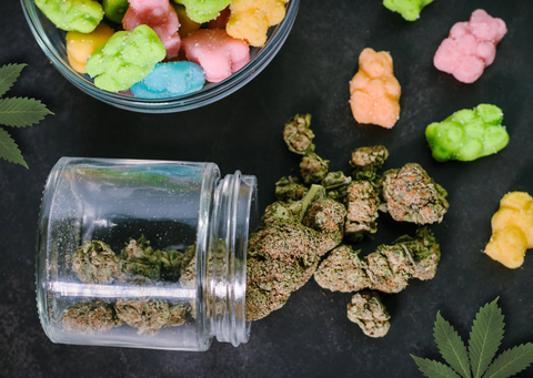 a jar of cannabis buds spilling out onto a table of coloured gummie bears