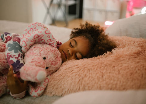 young child sleeping and holding a stuffed elephant