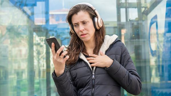 Woman looking at her phone with concerned look and hand over her heart