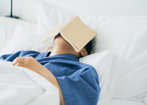 indeterminate race and gender person asleep with open book on their face