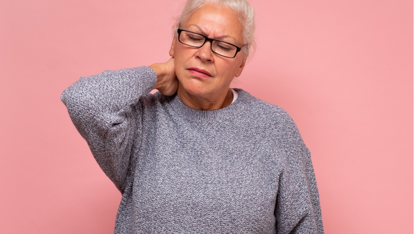 Middle aged woman with pained look on her face, holding her neck