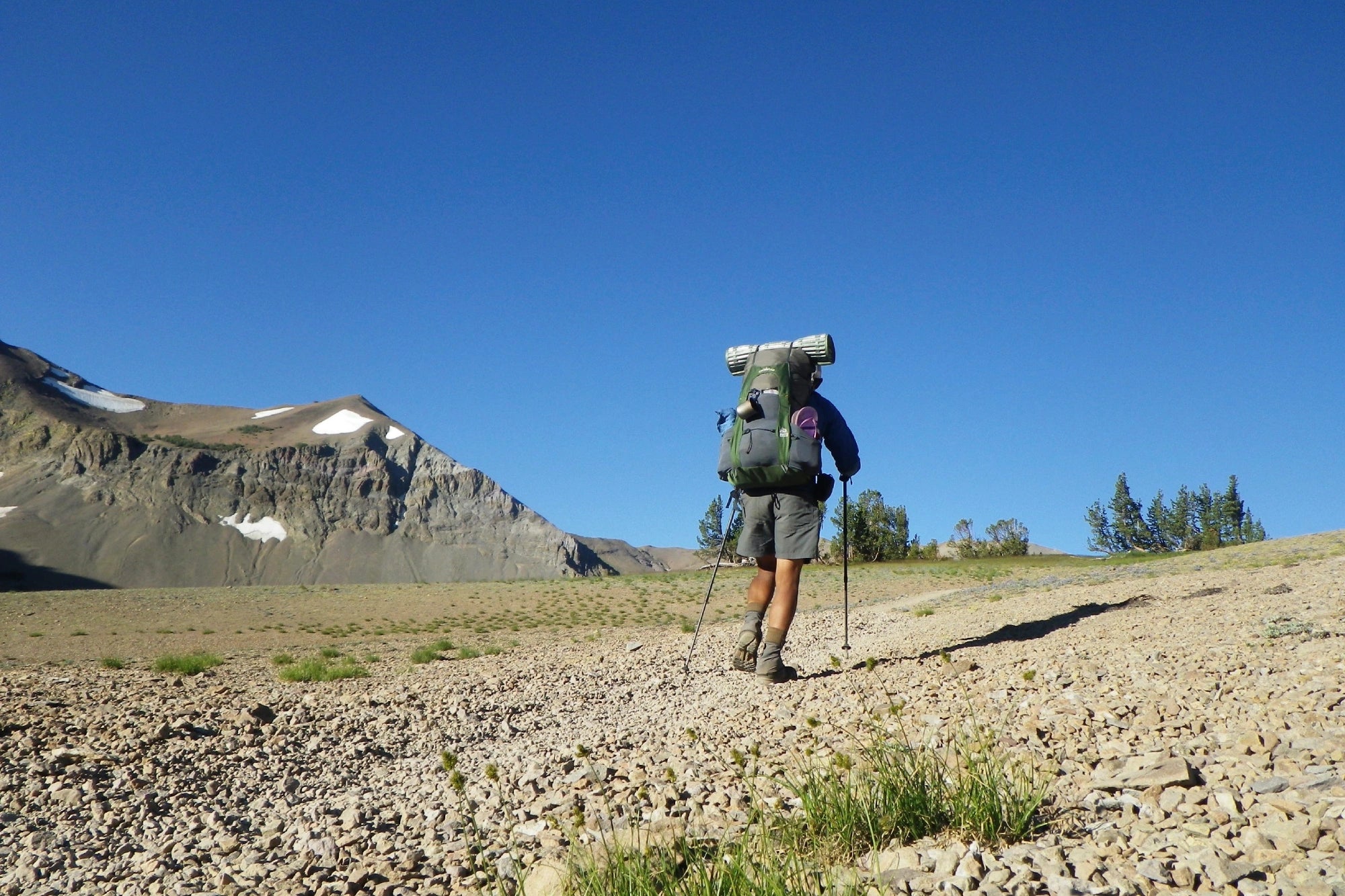 A hiker with a large pack walking through a vast, arid landscape