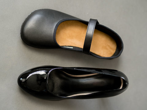 A classic narrow high heel next to a barefoot ballet flat.
