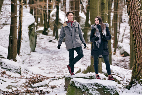 A woman and man on a walk through the winter forest in barefoot shoes